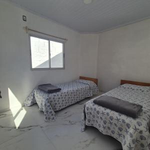 una habitación con dos camas y una ventana en Casa en el centro de Piriapolis a 1 cuadra de la playa, en Piriápolis 1 foto más