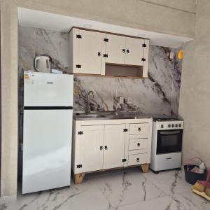 Una cocina con gabinetes blancos y un refrigerador blanco. en Casa en el centro de Piriapolis a 1 cuadra de la playa, en Piriápolis