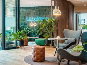 eine Lobby mit Stühlen, Tischen und Pflanzen in der Unterkunft Mercure Paris Montparnasse Pasteur in Paris