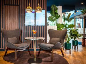 einen Tisch mit Stühlen und ein Glas Wein darauf in der Unterkunft Mercure Paris Montparnasse Pasteur in Paris