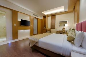 a hotel room with a bed and a television at Kiscol Grands Hotel in Coimbatore
