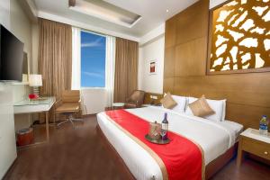 a hotel room with a large bed with a red blanket at Kiscol Grands Hotel in Coimbatore