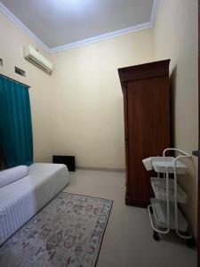 a bedroom with a bed and a cabinet and a rug at Raphi house in Yogyakarta