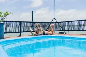 a woman is sitting next to a swimming pool at Mayan Monkey Cancun - Social Hotel in Cancún