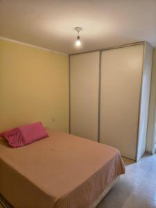 ein Schlafzimmer mit einem Bett, auf dem ein rotes Kissen liegt in der Unterkunft Quique1 in Pilar