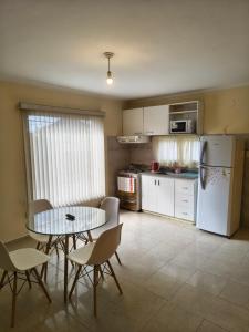 eine Küche mit Tisch, Stühlen und Kühlschrank in der Unterkunft Quique1 in Pilar
