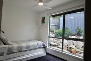 a bedroom with a bed and a large window at Paradise - Spacious, Ocean Views, Outdoor Living in Dodges Ferry