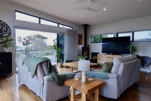 a living room with two couches and a tv at Paradise - Spacious, Ocean Views, Outdoor Living in Dodges Ferry