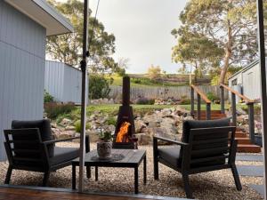 a patio with two chairs and a fire pit at Paradise - Spacious, Ocean Views, Outdoor Living in Dodges Ferry