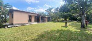 a house with a grass yard next to a building at Chácara mobiliada próximo Criciúma Br101 in Araranguá