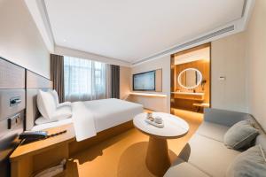 um quarto de hotel com uma cama, uma mesa e um sofá em JI Hotel Shanghai Nanxiang Guyi Garden em Xangai