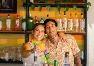 a man and woman standing behind a bar with a drink at Mayan Monkey Tulum - Social Hotel in Tulum +3 photos