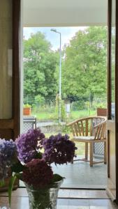 een vaas met paarse bloemen en een stoel op een veranda bij Villa Due Cieli 1 in Lanzo dʼIntelvi +5 foto's