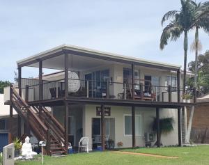 ein großes Haus mit einem Balkon und einer Terrasse in der Unterkunft Sensational Waterfront Apartment in Dunbogan