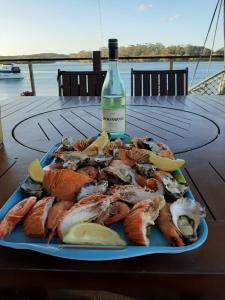 einen Teller mit Meeresfrüchten und eine Flasche Wein in der Unterkunft Sensational Waterfront Apartment in Dunbogan + 14 Fotos
