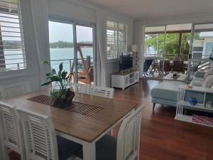 ein Wohnzimmer mit Tisch, Stühlen und Sofa in der Unterkunft Sensational Waterfront Apartment in Dunbogan