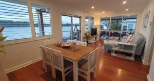 ein Wohnzimmer mit Tisch, Stühlen und Sofa in der Unterkunft Sensational Waterfront Apartment in Dunbogan