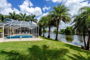 a house with a swimming pool and palm trees at Alecia in Cape Coral