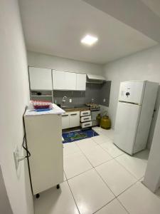 a kitchen with white cabinets and a refrigerator at Pé na Guarita in Torres
