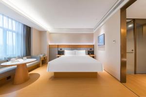 um quarto com uma grande cama branca e uma escrivaninha em JI Hotel Shanghai Nanxiang Guyi Garden em Xangai