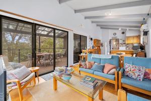 a living room with blue couches and a table at Treehouse at Cape in Cape Paterson