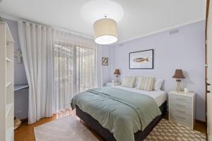 a white bedroom with a bed and a window at Treehouse at Cape in Cape Paterson