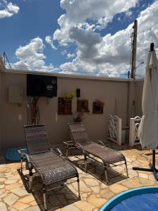 een terras met drie stoelen en een tv en een zwembad bij Casa Magnífica in Olímpia
