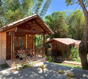 a small cabin with a porch and a tree at Monte Suiço - Chalés para locação in Guaramiranga