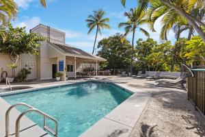 a swimming pool with palm trees and a house at The Landing at Kailua Bay in Kailua-Kona