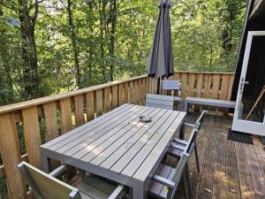 uma mesa de madeira e cadeiras num deque com um guarda-sol em Lovely Private Chalet near Durbuy em Septon