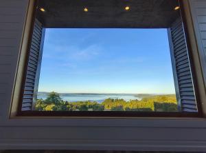 una ventana en una habitación con vistas al agua en Refugio Maẅen, en Puqueldón