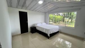 a bedroom with a bed and a large window at Hotel Campestre Cinco Estrellas in Villavicencio