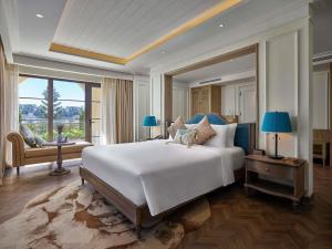 a bedroom with a large bed and a large window at Mercure Dalat Resort in Da Lat