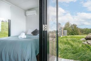 a bedroom with a bed and a view of a field at Aorangi Peak Cabins 2 by Tiny Away in Rotorua