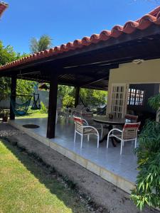 a patio with a table and chairs under a roof at Casa do Sonho in Paripueira