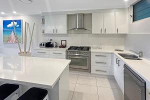 Una cocina blanca con fregadero y estufa. en Poinciana Lodges, en Hamilton Island