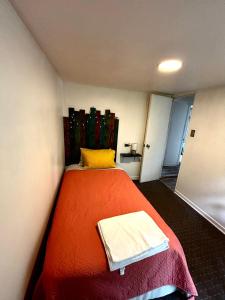 a bedroom with a orange bed with a yellow pillow at Cabaña en el bosque, Valdivia in Valdivia