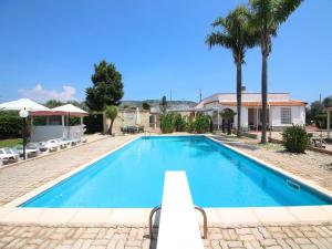 a swimming pool in a villa with palm trees at Spacious villa with a large veranda and pool in Floridia
