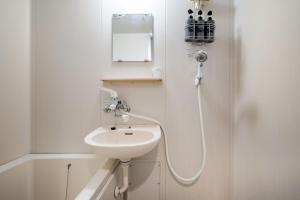 a white bathroom with a sink and a mirror at Casa Kiwa Room 101 in Fuchu +25 photos