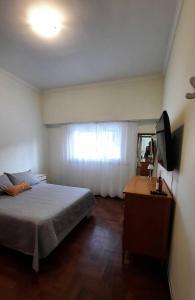 Mar de Ajó hostal في مار دي آخو: غرفة نوم بسرير وخزانة وتلفزيون