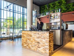 Un hombre hablando por teléfono en un bar de un edificio. en Ibis Marseille Marignane Technopole, en Marignane
