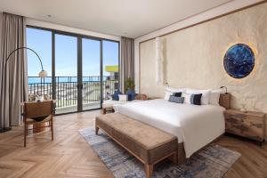 a bedroom with a large bed and a large window at Hoi An Royal Beachfront Resort & Villas in Dien Ban