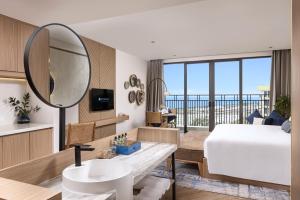 a bedroom with a bed and a sink and a mirror at Hoi An Royal Beachfront Resort & Villas in Dien Ban