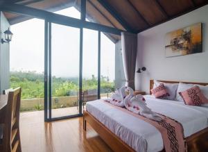 two beds in a room with a large window at Alam Munduk Cabin in Munduk