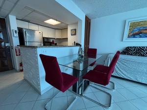 una cucina con tavolo in vetro e sedie rosse di Ocean View Apartment inside ESJ Hotel a San Juan