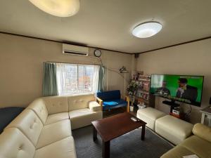Private Retreat Nagasaki Vogelnest 2階貸切屋上テラス貸切長崎スタジアム5分 في ناغاساكي: غرفة معيشة مع أريكة بيضاء وتلفزيون بشاشة مسطحة