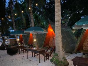 Alfonsa Tent Ground - Camp By The Sea في أوسلوب: مجموعة طاولات ومظلات على الشاطئ