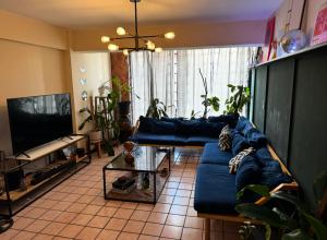 een woonkamer met een blauwe bank en een tv bij Habitación en Depto chic compartido in Villahermosa