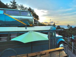 a blue van with an umbrella on top of it at El Destino - Rooftop Converted Chicken Bus in San Marcos La Laguna +25 photos