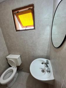 Un baño con inodoro, lavabo y espejo. en Zakk Casa de Playa, en Necochea 7 fotos más